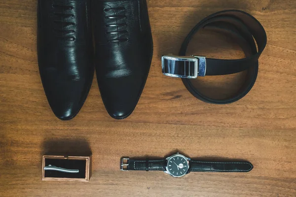 Men's accessories: watch, tie, belt, shoes top view.
