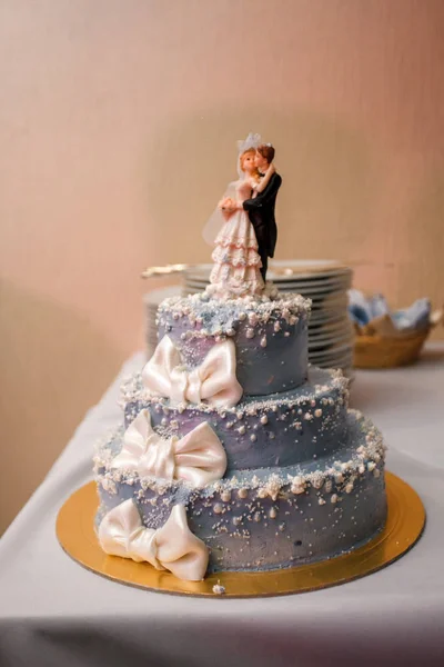 Tiered wedding cake with figurines of the bride and groom.