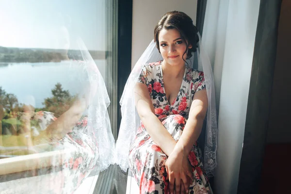 Portrait of a beautiful young bride in a hotel room near a large — Stock Photo, Image