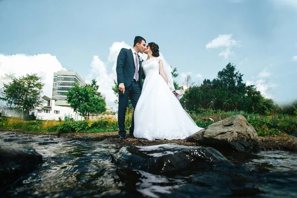 Hermosa pareja de recién casados cerca del agua. Licitación y tacto —  Fotos de Stock