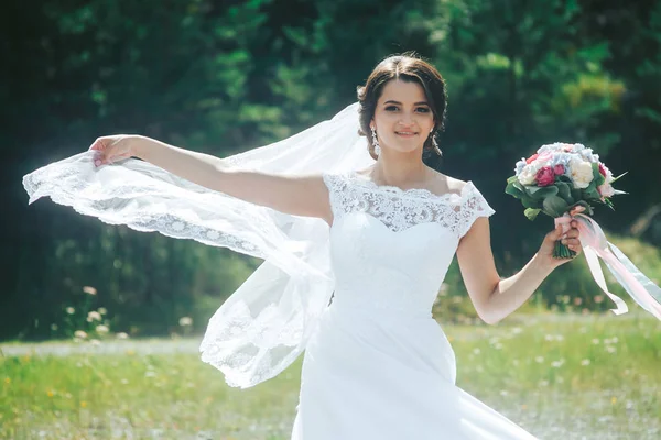 Portrét krásné šťastné nevěsty proti zelené louce a f — Stock fotografie