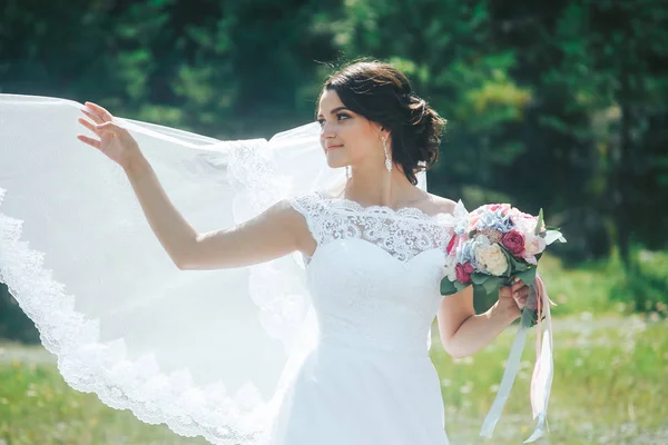 Portrét krásné šťastné nevěsty proti zelené louce a f — Stock fotografie