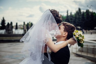 Arkadaki beyaz elbiseli yakışıklı bir eş tutan mutlu damat