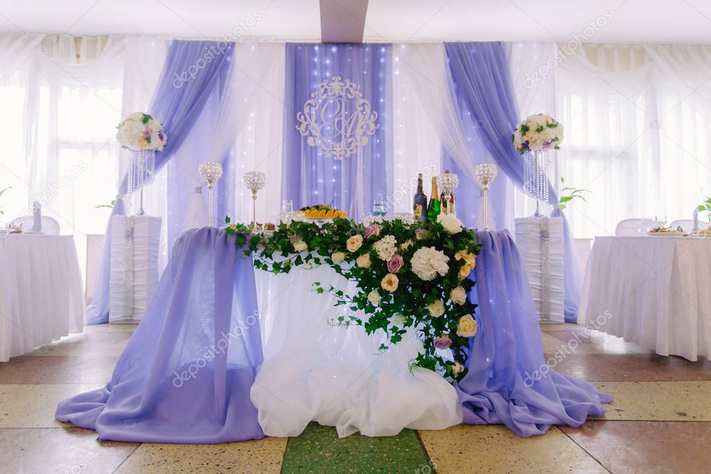 Festive table for the bride and groom decorated in a luxury style with glosses, blue cloth, and flowers. With inscription Dream come true. Indoor