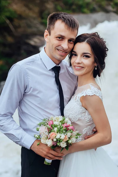 Bello ritratto di felice sposa e sposo in natura su sfondo cascata — Foto Stock