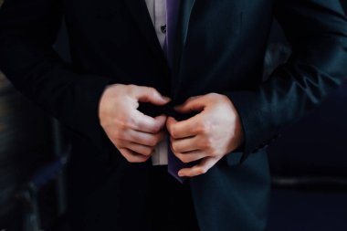 Buttoning a jacket hands close up. Stylish man in suit fastens b