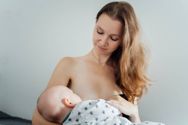 Güzel genç anne bebeğini evde emziriyor.