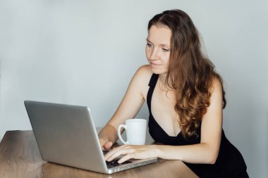 Genç, güzel, üzgün bir kız bir dizüstü bilgisayarın önünde oturuyor.