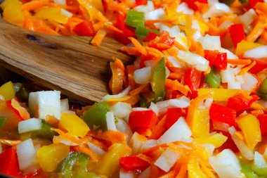 Taze kesilmiş sebzeler: biber, soğan, havuç, tavada.