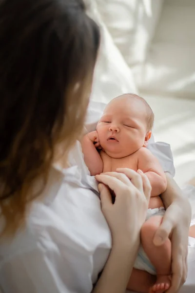 Güzel bir kadın kucağında yeni doğmuş bir bebeği tutuyor. — Stok fotoğraf