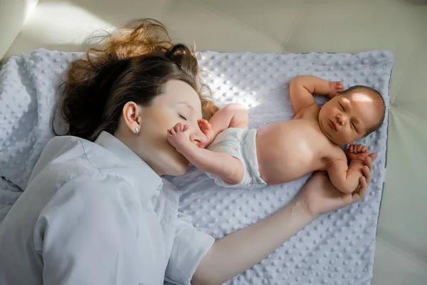 A young mother and a newborn boy are lying nearby. Mothers Day — Stock Photo, Image