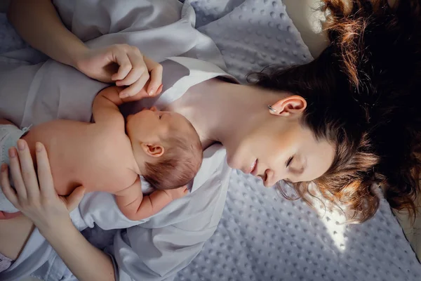 Новорожденный мальчик лежит на маминой груди. В светлой комнате. На солнце — стоковое фото