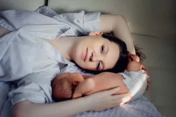 Eine junge Mutter und ein neugeborener Junge liegen in der Nähe. Muttertag — Stockfoto