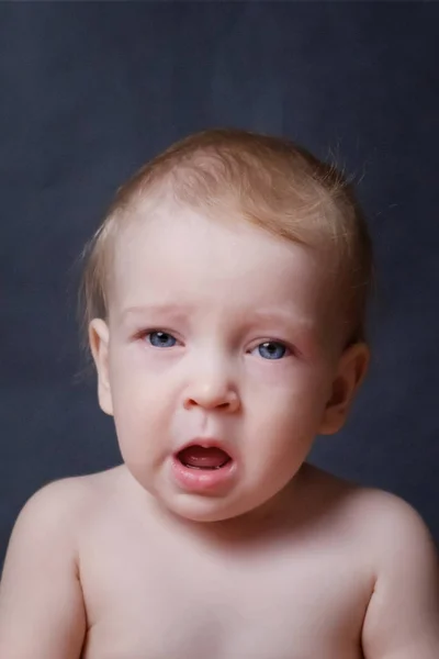 O bebé quer espirrar. Retrato de uma criança em um backgrou escuro — Fotografia de Stock