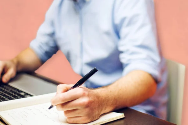 Hand of anonymous man holding nice pen and writing on paper sheet