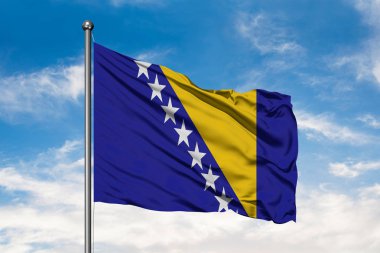 Flag of Bosnia-Herzegovina waving in the wind against white cloudy blue sky. Bosnian flag. clipart
