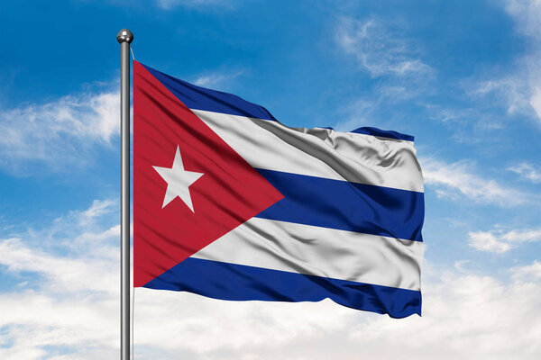 Flag of Cuba waving in the wind against white cloudy blue sky. Cuban flag.
