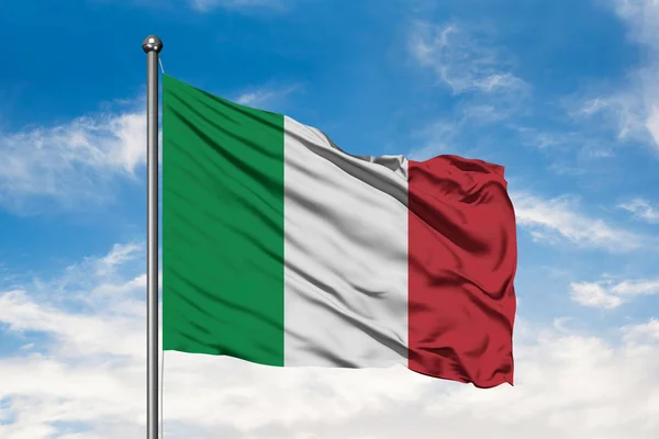 Flag of Italy waving in the wind against white cloudy blue sky. Italian flag.