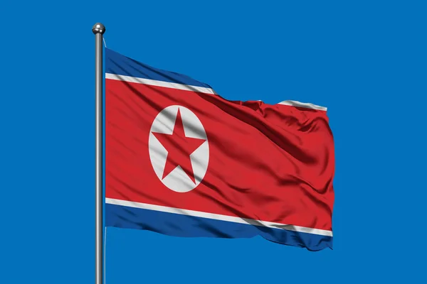 Flag of North Korea waving in the wind against deep blue sky. North Korean flag.