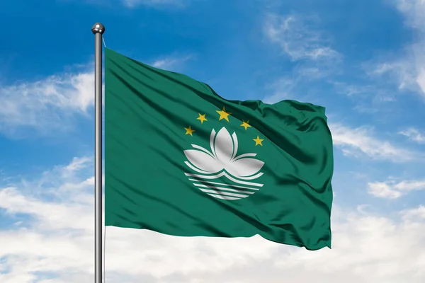 Flag of Macao waving in the wind against white cloudy blue sky. Macao Special Administrative Region flag.