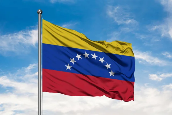 Flag of Venezuela waving in the wind against white cloudy blue sky. Venezuelan flag.