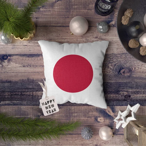 Happy New Year tag with Japan flag on pillow. Christmas decoration concept on wooden table with lovely objects.
