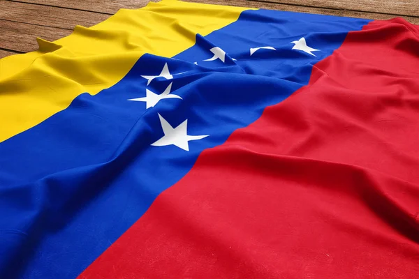 Flag of Venezuela on a wooden desk background. Silk Venezuelan flag top view.