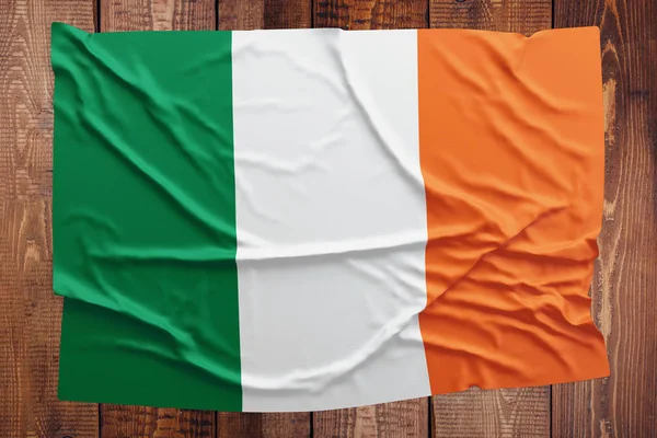 Flag of Ireland on a wooden table background. Wrinkled Irish flag top view.