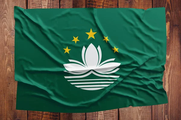 Flag of Macao on a wooden table background. Wrinkled Macau flag top view.