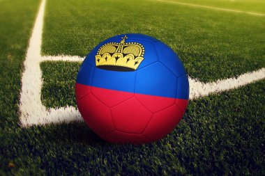 Lihtenştayn topu köşe vuruşu pozisyonunda, futbol sahası arka planı. Yeşil çimüzerinde ulusal futbol teması.