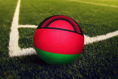 Malavi topu köşe vuruşu pozisyonunda, futbol sahası arka planı. Yeşil çimüzerinde ulusal futbol teması.