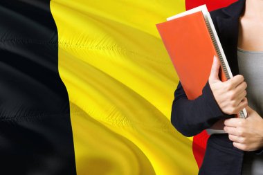 Belçikalı dil kavram öğrenme. Belçika bayrağı arka planda duran genç kadın. Kitaplar, turuncu boş kitap kapağı tutan öğretmen.