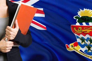 Öğrenme dil kavram. Cayman Adaları bayrağı arka planda duran genç kadın. Kitaplar, turuncu boş kitap kapağı tutan öğretmen.