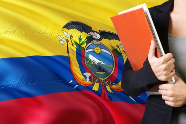 Öğrenme Ekvatorlu dil kavram. Ekvador bayrağı arka planda duran genç kadın. Kitaplar, turuncu boş kitap kapağı tutan öğretmen.