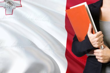 Malta dil kavram öğrenme. Malta bayrağı arka planda duran genç kadın. Kitaplar, turuncu boş kitap kapağı tutan öğretmen.