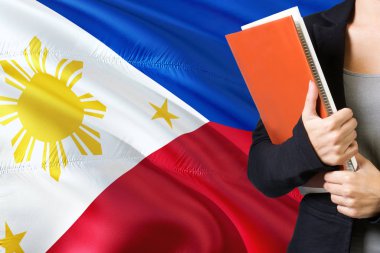 Filipino dil kavram öğrenme. Filipinler bayrağı arka planda duran genç kadın. Kitaplar, turuncu boş kitap kapağı tutan öğretmen.