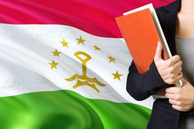Öğrenme Tacik Dili kavramı. Tacikistan bayrağı arka planda duran genç kadın. Kitaplar, turuncu boş kitap kapağı tutan öğretmen.