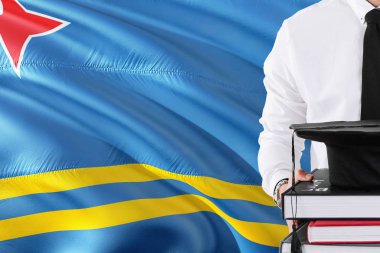 Başarılı öğrenci eğitim kavramı. Aruba bayrağı arka plan üzerinde tutan kitaplar ve mezuniyet kep.
