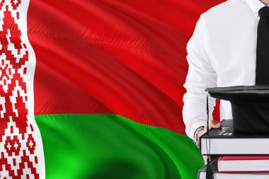 Başarılı Belarus öğrenci eğitim kavramı. Beyaz Rusya bayrağı arka plan üzerinde tutan kitaplar ve mezuniyet kep.