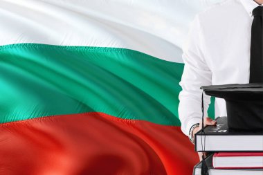 Başarılı Bulgar öğrenci eğitim kavramı. Bulgaristan bayrağı arka plan üzerinde tutan kitaplar ve mezuniyet kep.