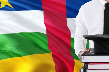 Başarılı öğrenci eğitim kavramı. Orta Afrika Cumhuriyeti bayrağı arka plan üzerinde tutan kitaplar ve mezuniyet kep.