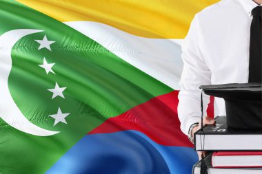 Başarılı Comoran öğrenci eğitim kavramı. Komor bayrağı arka plan üzerinde tutan kitaplar ve mezuniyet kep.