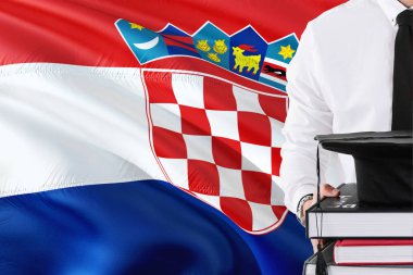 Başarılı Hırvat öğrenci eğitim kavramı. Hırvatistan bayrağı arka plan üzerinde tutan kitaplar ve mezuniyet kep.