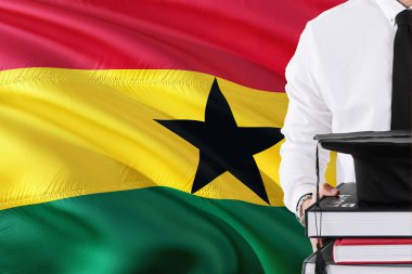Başarılı Ganalı öğrenci eğitim kavramı. Elinde kitap ve mezuniyet Gana bayrak arka plan üzerinde kap.
