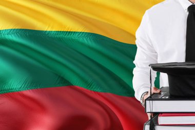 Başarılı Litvanyalı öğrenci eğitim kavramı. Litvanya bayrağı arka plan üzerinde tutan kitaplar ve mezuniyet kep.