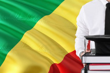 Başarılı öğrenci eğitim kavramı. Kongo Cumhuriyeti bayrağı arka plan üzerinde tutan kitaplar ve mezuniyet kep.