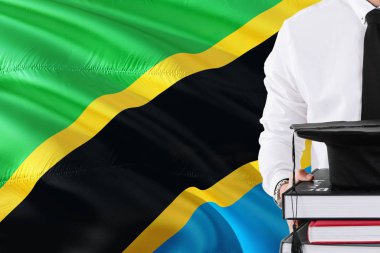 Başarılı Tanzanya öğrenci eğitim kavramı. Tanzanya bayrak arka plan üzerinde tutan kitaplar ve mezuniyet kep.