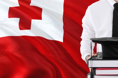 Başarılı Tonga öğrenci eğitim kavramı. Tonga bayrak arka plan üzerinde tutan kitaplar ve mezuniyet kep.