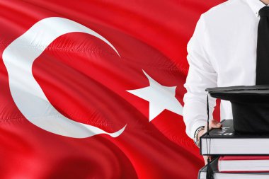 Başarılı Türk öğrenci eğitim kavramı. Elinde kitap ve mezuniyet Türkiye bayrağı arka plan üzerinde kap.