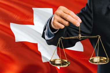 Swiss Yargıç adaletin altın terazisi ile İsviçre bayrağı arka plan sallayarak tutuyor. Eşitlik Tema ve yasal kavram.